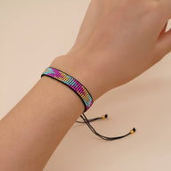 Bracelet ajustable en perles rondes multicolores aux tons rose, bleu, jaune sur cordon noir avec fermoir coulissant.