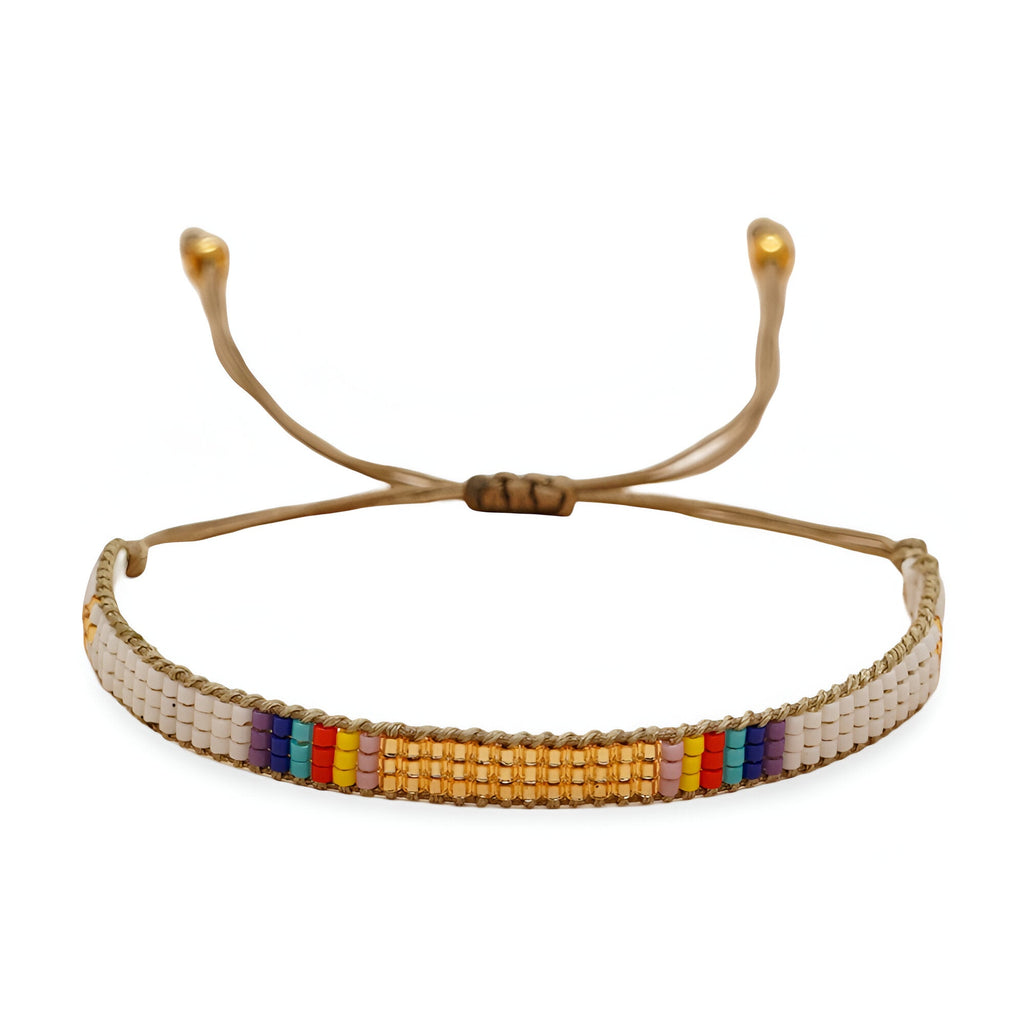 Bracelet ajustable en perles rondes blanches, or et multicolores sur fil beige.