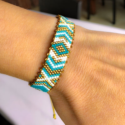 Bracelet ajustable en perles japonaises bleues, blanches et dorées avec motif géométrique arrondi.