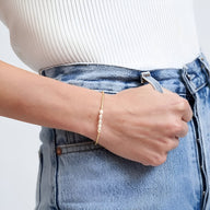 Bracelet fin en perles dorées japonaises portées au poignet, style élégant et minimaliste.