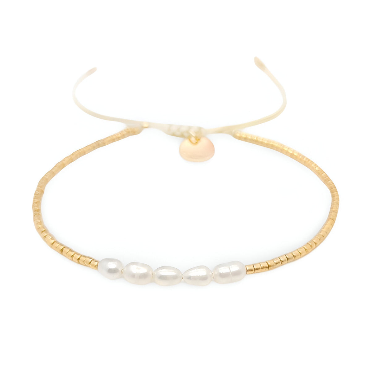 Bracelet fin en perles dorées avec six perles blanches ovales centrales et fermoir coulissant pigment crème.