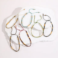 Set de sept bracelets double-rangs ajustables en perles du Japon coloris beige, noir, bleu, bordeaux, marron et vert.