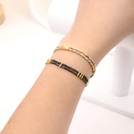 Bracelet double-rangs ajustable en perles japonaises, un rang beige clair et un rang noir avec détails dorés.