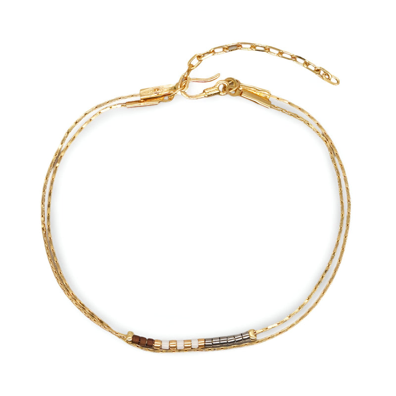 Bracelet double-rangs en perles noires et blanches avec chaîne dorée ajustable.