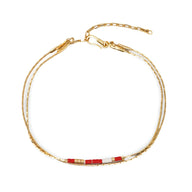 Bracelet double-rangs en perles rouges et blanches avec chaîne dorée réglable.