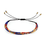 Bracelet multi-rangs en perles colorées rouge, bleu et doré avec cordon noir ajustable.