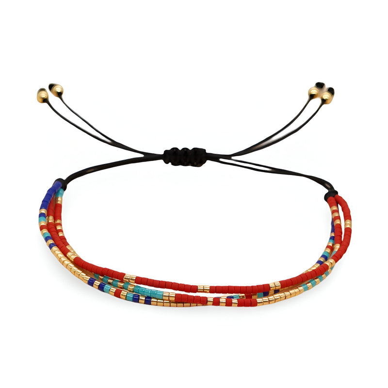 Bracelet multi-rangs en perles colorées rouges, bleues et dorées avec cordon noir ajustable.