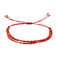 Bracelet multi-rangs rouge en perles avec fines bagues dorées et fermoir coulissant rouge.