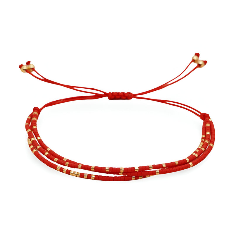 Bracelet multi-rangs rouge en perles avec fines bagues dorées et fermoir coulissant rouge.
