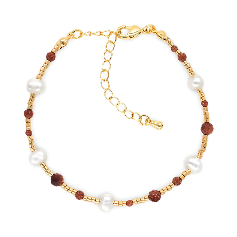 Bracelet fin en perles blanches et pierres de grès marron sur chaîne dorée avec fermoir réglable.