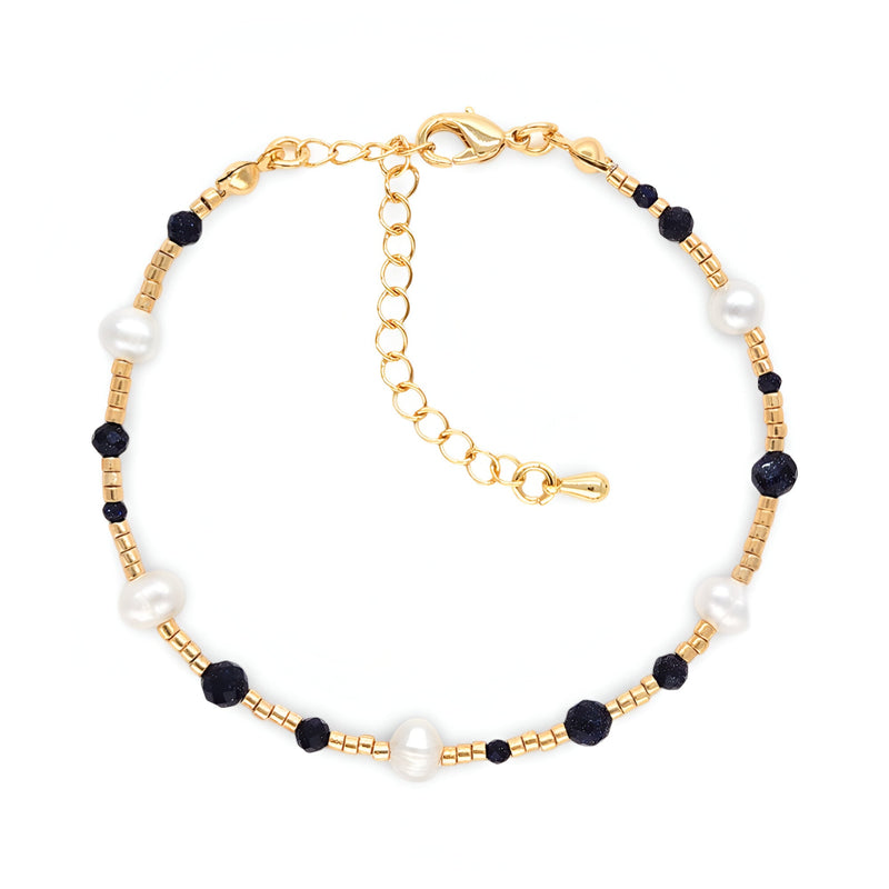 Bracelet fin en perles blanches et noires avec pierre de grès, fermoir doré ajustable.