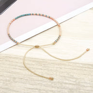 Bracelet fin avec perles turquoise et dorées, cordon beige ajustable en tissu doux.