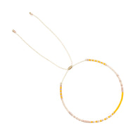 Bracelet ajustable en perles japonaises jaunes et blanches avec fil doré fin.