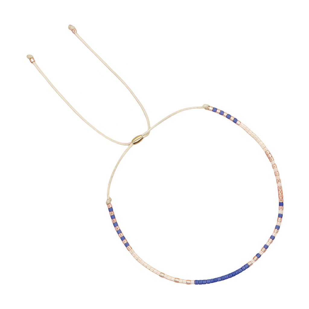 Bracelet réglable en perles fines beige et bleu avec fil doré délicat.