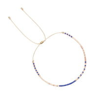 Bracelet réglable en perles fines beige et bleu avec fil doré délicat.