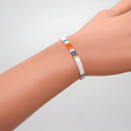 Bracelet fin en perles multicolores carrées, tons blanc, orange, violet et bleu, style minimaliste féminin.