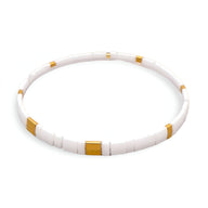 Bracelet fin en perles blanches et dorées, design minimaliste et élégant pour femme.