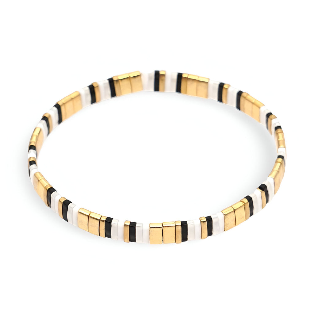 Bracelet fin en perles dorées, blanches et noires, style minimaliste et élégant.