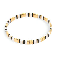 Bracelet fin en perles dorées, blanches et noires, style minimaliste et élégant.