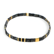 Bracelet fin en perles noires et dorées style japonais, motif géométrique élégant.