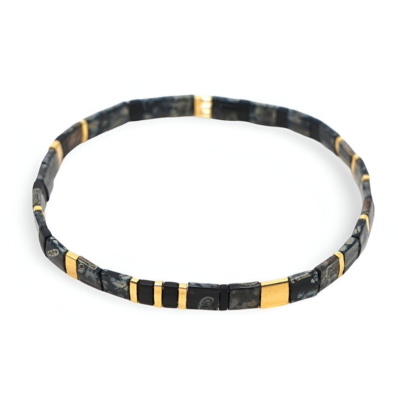 Bracelet fin en perles noires et dorées style japonais, motif géométrique élégant.