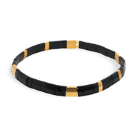 Bracelet élastique femme en perles noires et dorées, style minimaliste et moderne.