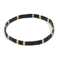 Bracelet pour femme en perles noires et dorées, style minimaliste et moderne.
