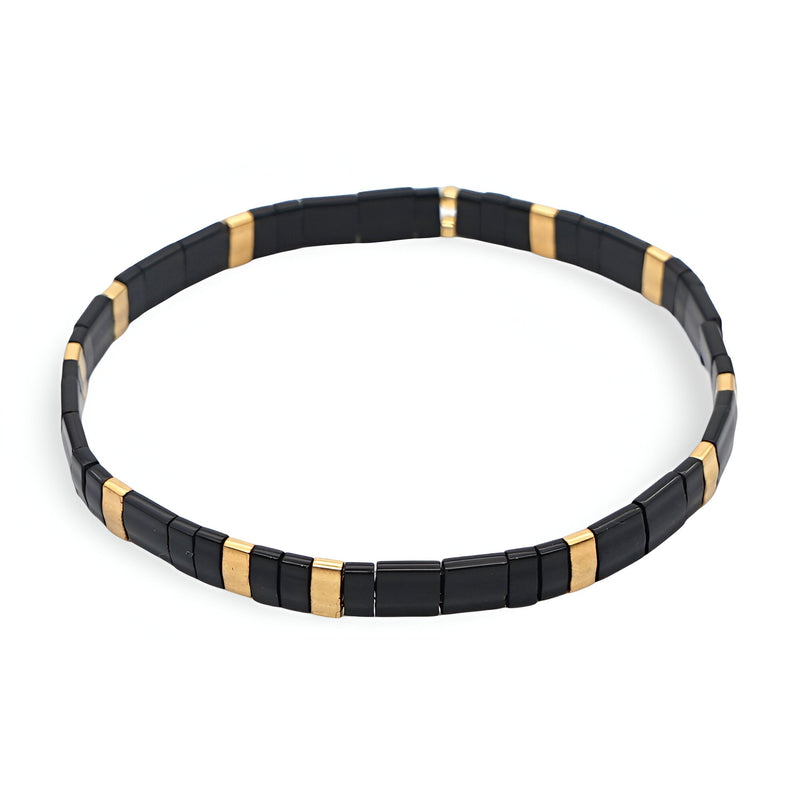Bracelet pour femme en perles noires et dorées, style minimaliste et moderne.