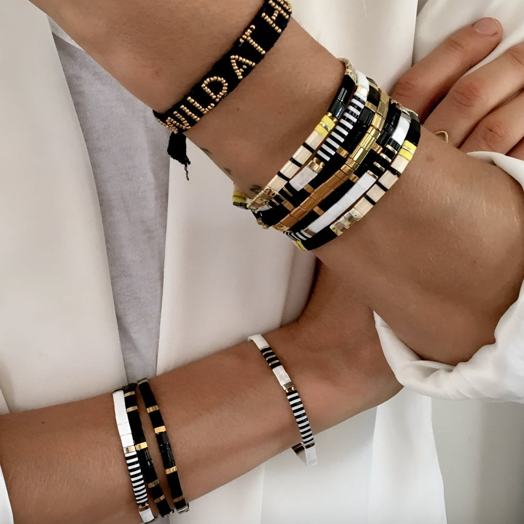 Bracelet femme en perles noires, blanches et or, design Emi avec motif graphique élégant.