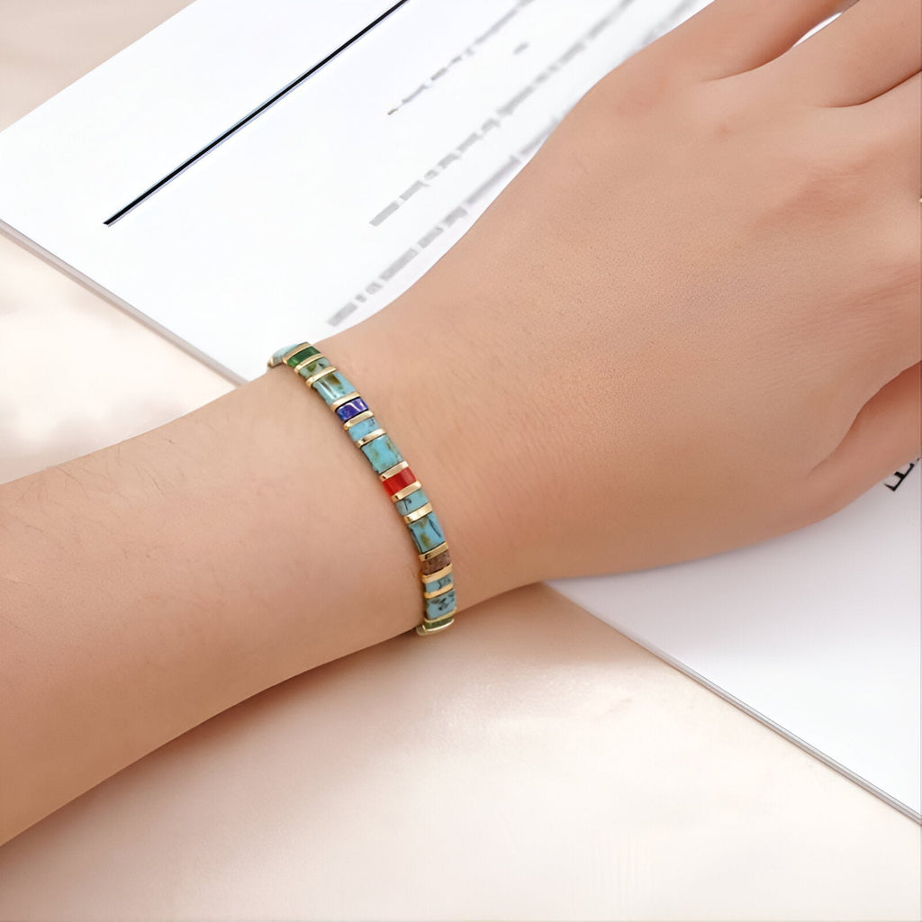 Bracelet ajusté en perles carrées multicolores bleu, vert et orange sur poignet féminin.