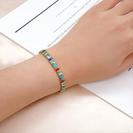 Bracelet ajusté en perles carrées multicolores bleu, vert et orange sur poignet féminin.