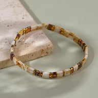 Bracelet fin en perles carrées marron et beige avec motifs dorés, style japonais élégant.