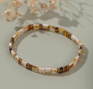 Bracelet fin en perles marron et ivoire avec détails bleu marine, style minimaliste élégant.