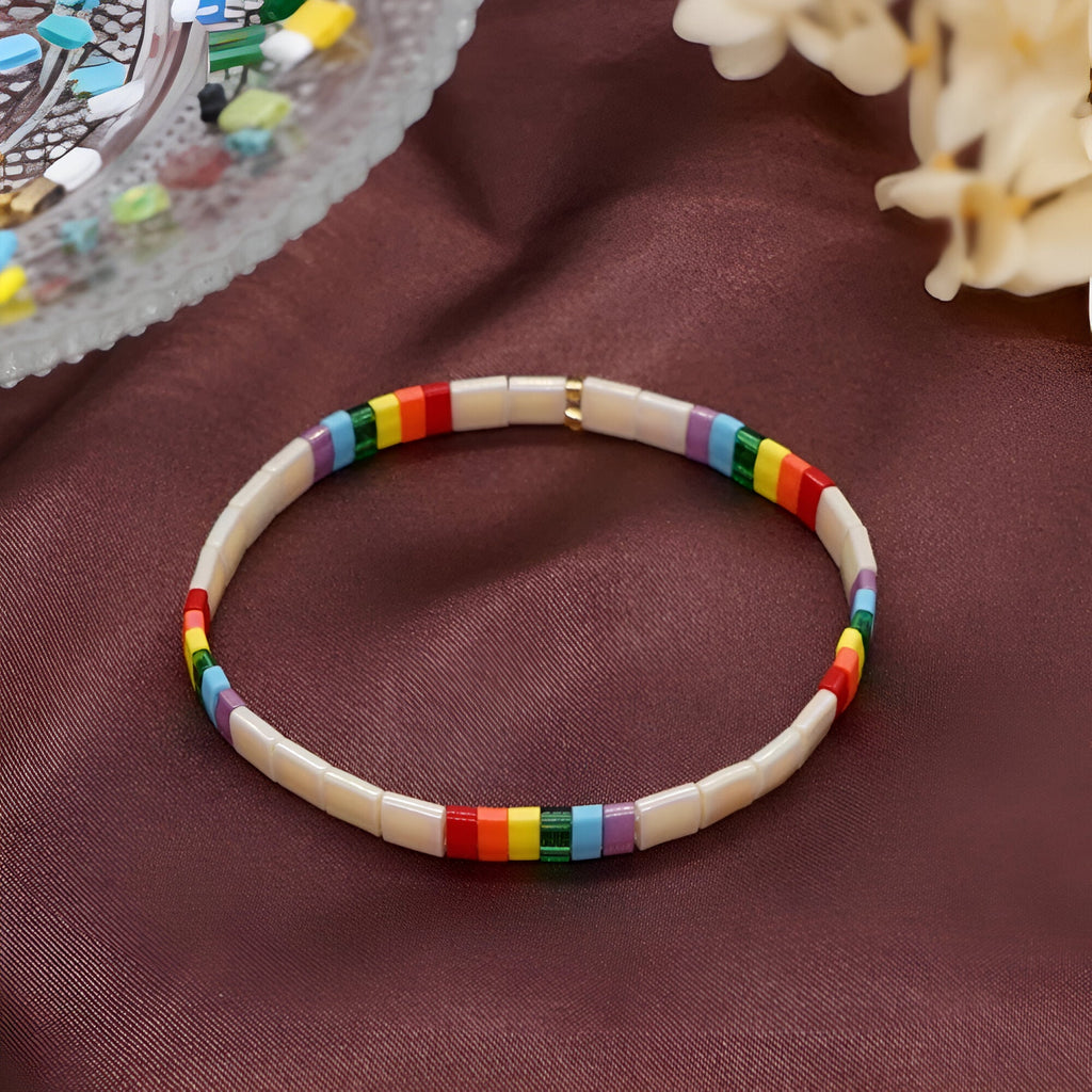 Bracelet fin en perles multicolores japonaises avec sections rouges, jaunes, vertes, bleues et blanches.