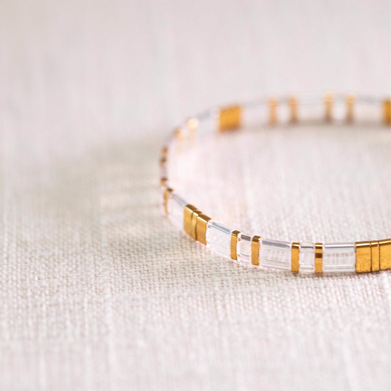 Bracelet fin en perles transparentes et dorées, style minimaliste élégant pour femme.