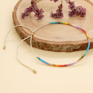 Bracelet fin en perles multicolores esprit Kumiko avec cordon beige ajustable et embouts dorés.