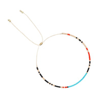 Bracelet fin en perles japonaises multicolores bleu, rouge, noir et beige avec cordon ajustable doré.