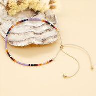 Bracelet ajustable en perles japonaises multicolores style Kumiko sur fond beige.