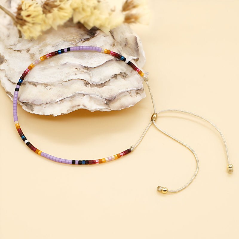 Bracelet ajustable en perles japonaises multicolores style Kumiko sur fond beige.