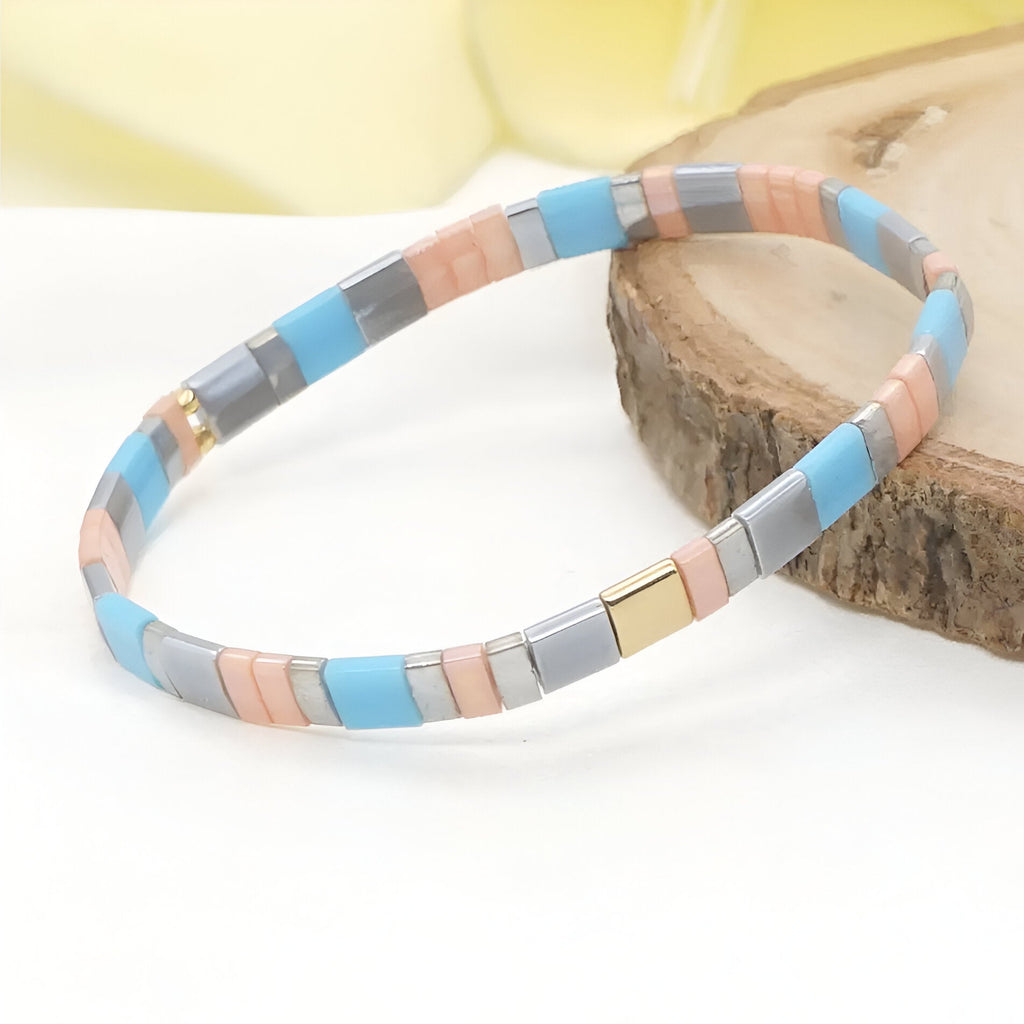 Bracelet rigide femme en perles plates bleu, gris, pêche et doré, style contemporain.