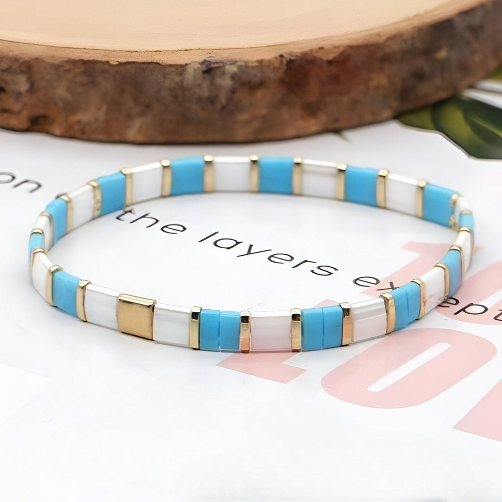Bracelet fin en perles carrées bleu, blanc et doré, style élégant pour femme.