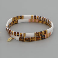 Bracelet double tour pour femme en perles plates blanches, mates et dorées avec petites touches roses et breloque feuille.