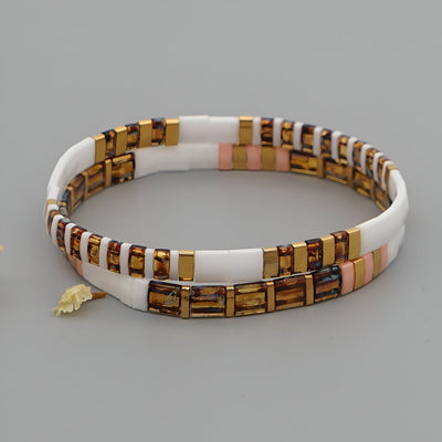 Bracelet double tour pour femme en perles plates blanches, mates et dorées avec petites touches roses et breloque feuille.