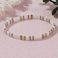 Bracelet fin en perles blanches et accents dorés, style élégant et minimaliste pour femme.