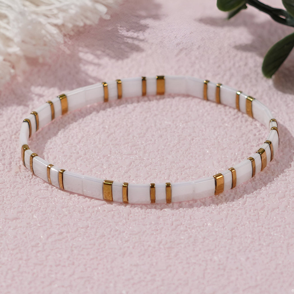 Bracelet fin en perles blanches et accents dorés, style élégant et minimaliste pour femme.