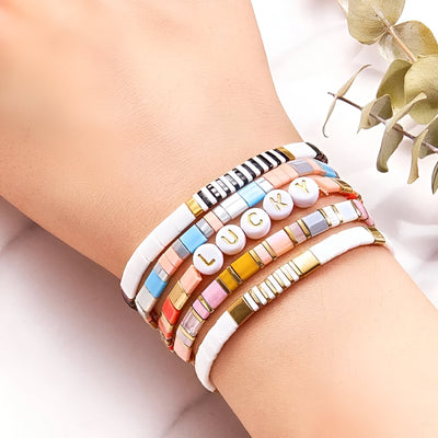Bracelet multi-rangs en perles colorées et lettres blanches formant "LOVE" sur poignet féminin.