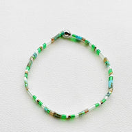 Bracelet fin pour femme en perles vertes et blanches avec fermoir argenté, style délicat.