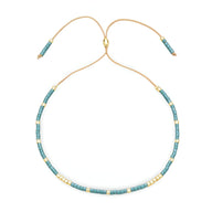 Bracelet ajustable en perles turquoise et dorées avec cordon beige fin.