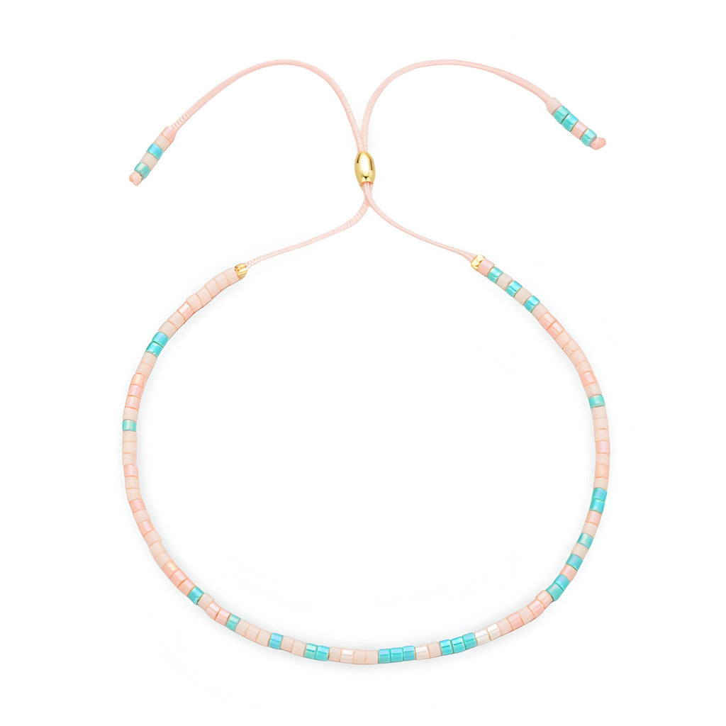 Bracelet fin en perles turquoise et rose clair avec fermoir doré et cordon ajustable rose pâle.