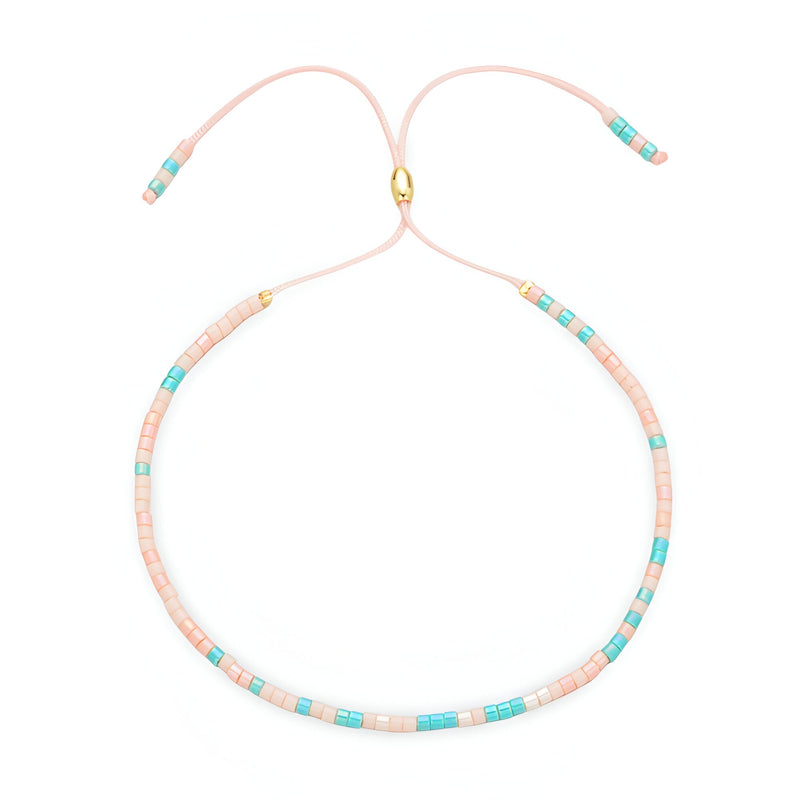Bracelet fin en perles turquoise et rose clair avec fermoir doré et cordon ajustable rose pâle.